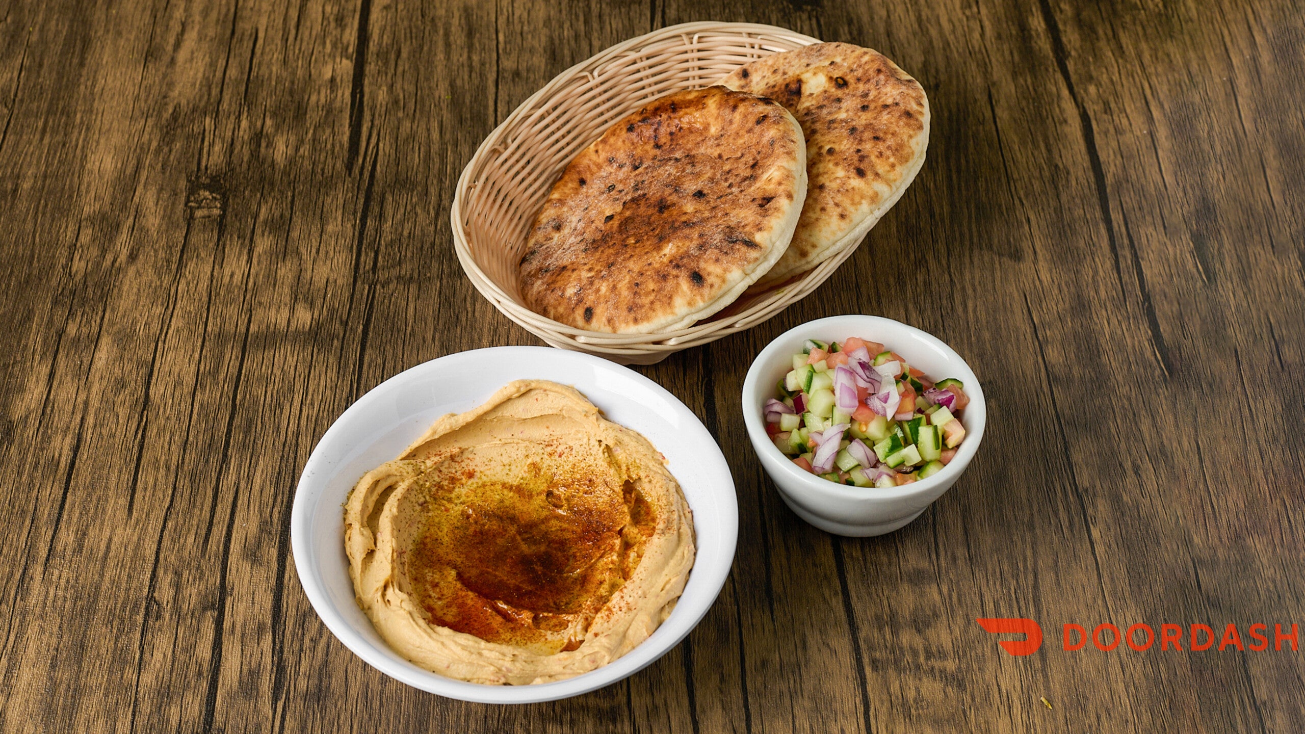 Pita bread on a wooden table with a small bowl of salad.