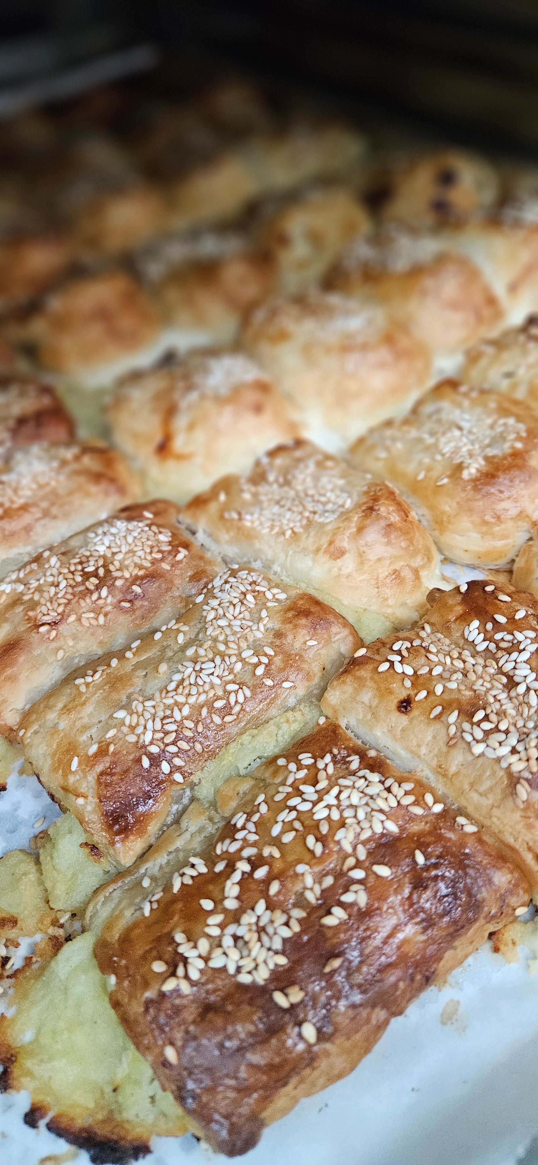 Baked cheese burekas with sesame seeds on a white plate