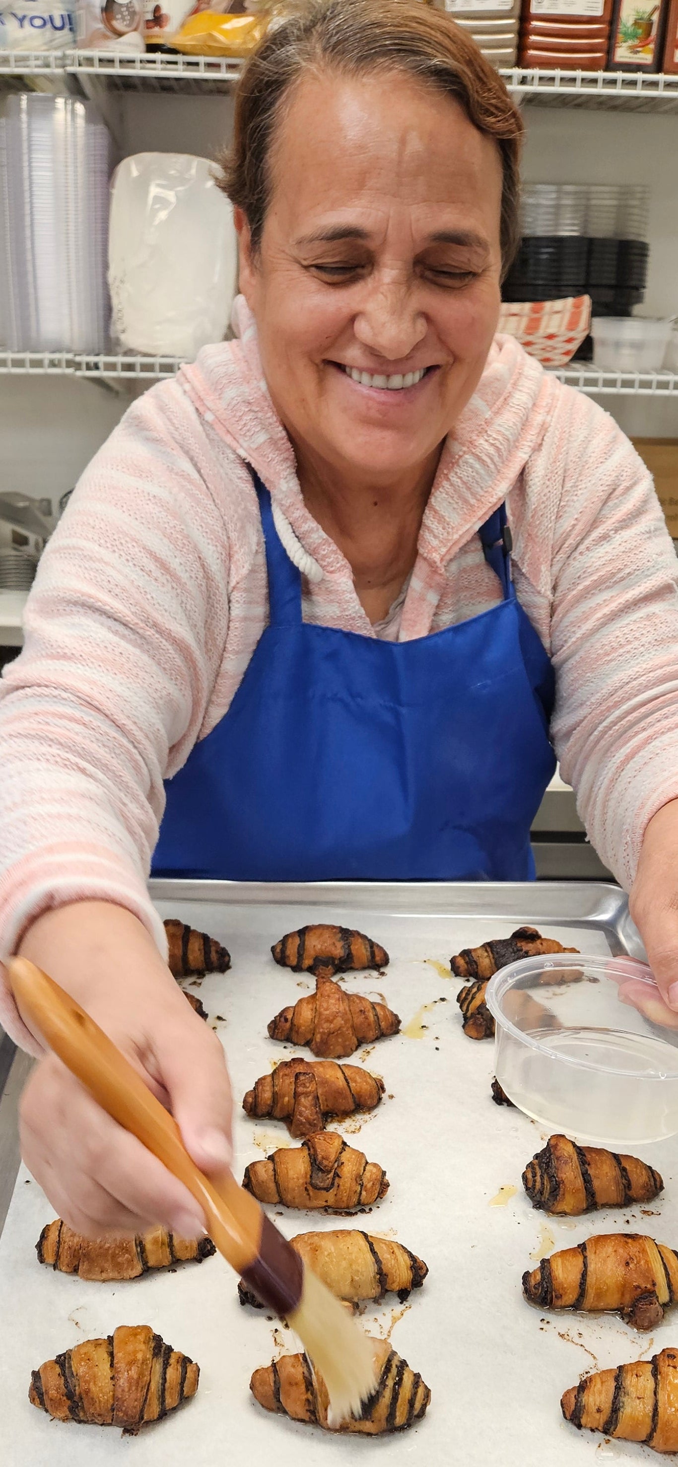 Woman in a kitchen preparing food, wearing a blue apron.