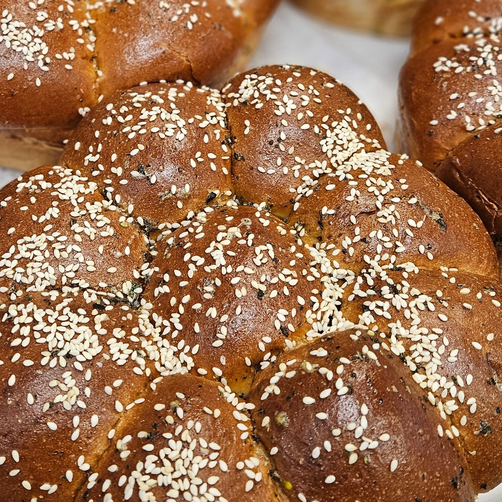 Baked bread rolls with sesame seeds on a metal tray