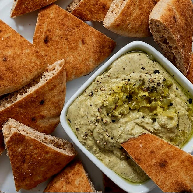 Plates of triangular bread slices with two dips on a patterned tablecloth.