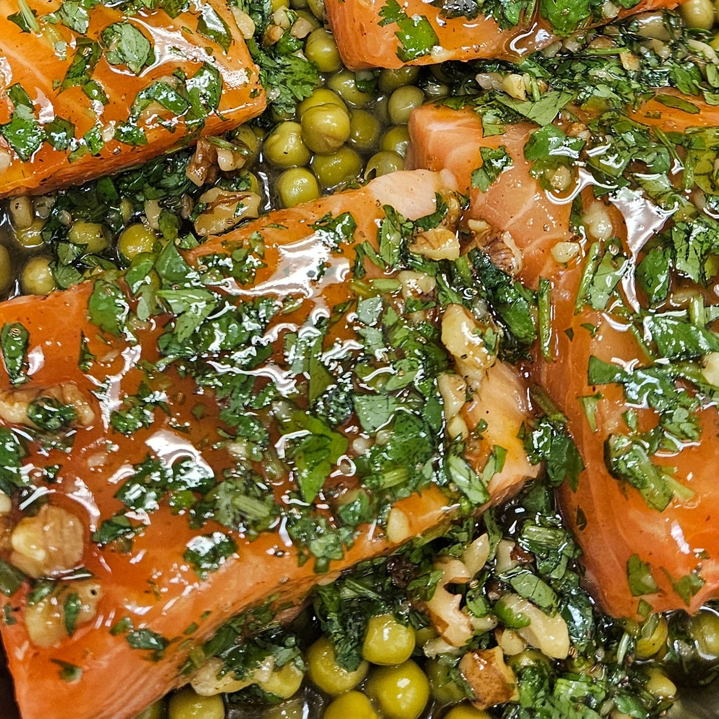 Salmon fillets with green herb sauce and peas on a glass plate