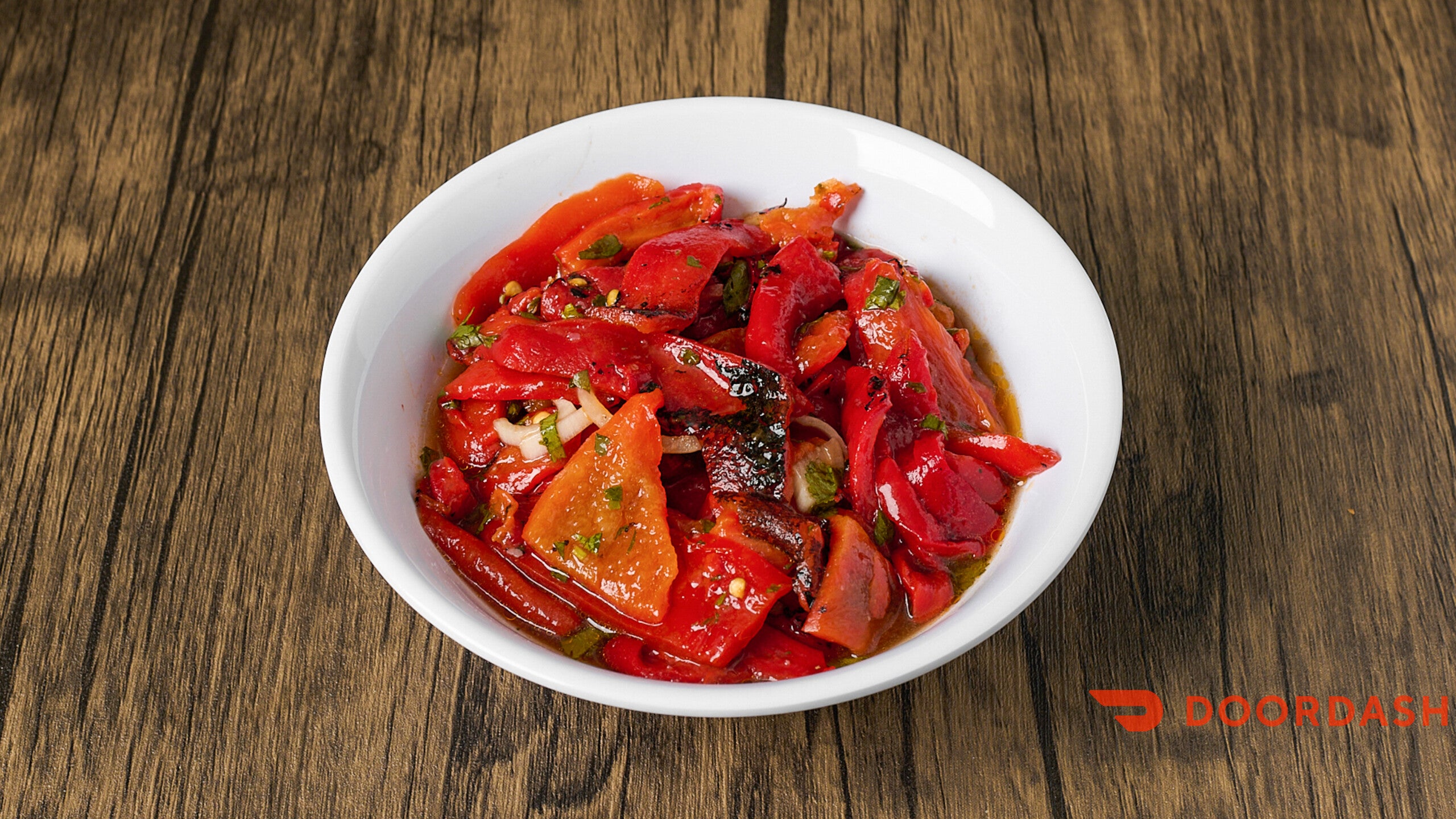 White bowl filled with red and orange salad on a wooden surface